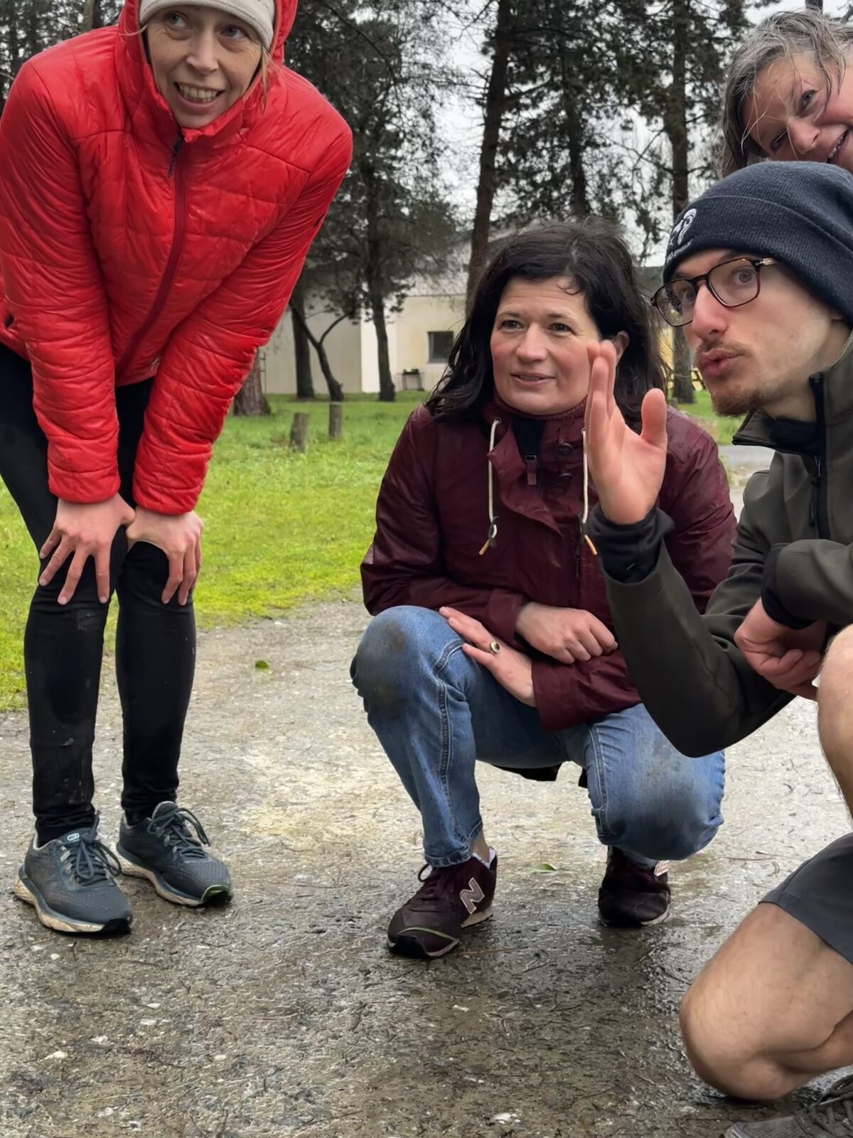 Trois adultes discutant sous la pluie en forêt