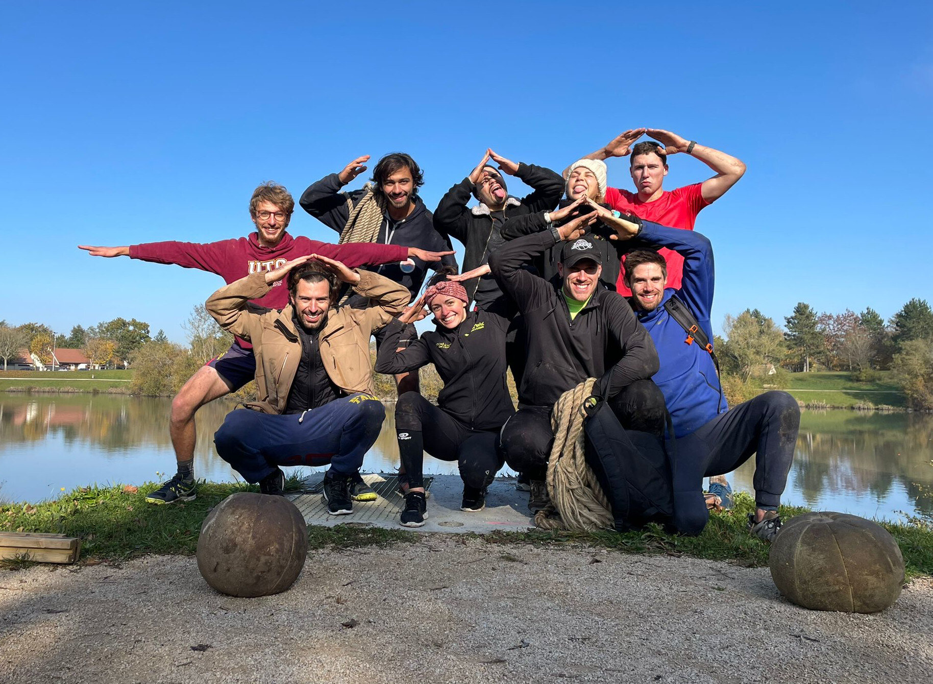 Groupe de moniteurs posant joyeusement au bord d'un étang après une session